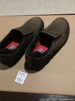 Pair of brown slip-on Skechers Work boots with padded collar, size 12, placed on cardboard.