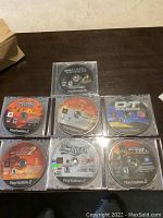 Nine PlayStation 2 game discs in clear jewel cases shown on dark surface