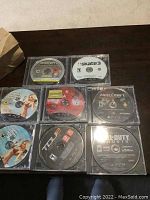 Photo showing eight PS3 game discs laid out on a wooden surface, two Grand Theft Auto discs, Skate 3, Minecraft, Resistance 2, Call of Duty Ghosts, NBA 2K15, Top Spin 4, Test Drive Unlimited 5.