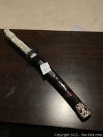 Full view of the replica Japanese katana sword in its black scabbard showing length and overall condition.