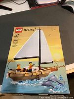 Front of the sealed LEGO Ideas 40487 Sailboat box showing the assembled sailboat, minifigures, and dolphins, with a yellow and blue background.