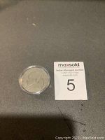 Obverse side of USA 1975 silver dollar coin in round protective plastic case, showing profile of President Eisenhower and inscription details.