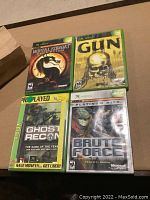 Four Xbox games arranged in two rows on a surface: Mortal Kombat Deception, Gun, Ghost Recon, and Brute Force Platinum Hits.