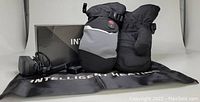 Photo shows a pair of black and gray rechargeable heated mittens with an attached power button, charger, and black storage pouch labeled 'INTELLIGENT HEATING'.