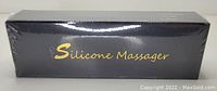 Photo of the sealed black box with gold text reading 'Silicone Massager' indicating the item inside is a silicone wand massager in burgundy.