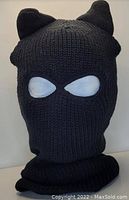 Black knitted ski mask with distinct cat ears and two eye openings made from white lining material. The mask includes coverage down to the neck area.