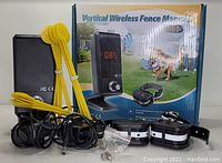 Photo showing boxed product Vertical Wireless Fence Manual S-35 with hub, 2 shock collars, boundary posts, cables, and mounting screws.