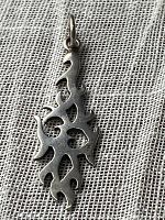 Front view of a stylized flame-shaped silver pendant laid on fabric background.