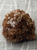Front view of the brown aragonite crystal cluster showing hexagonal shapes and compact formation.