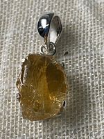Front close-up image of rough citrine crystal chunk pendant set in 925 sterling silver with silver bail, showing natural crystal textures and polish on bottom.
