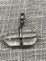 Clear quartz pendant with double terminated crystal mounted in silver, shown on white mesh fabric background.