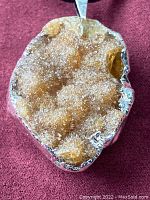 Close-up view of the druzy crystal pendant mounted in silver, showing sparkling crystals and the texture of the silver setting.