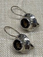 Pair of faceted smoky quartz earrings in 925 sterling silver on a textured fabric, shown from a slight top angle to highlight the stones.