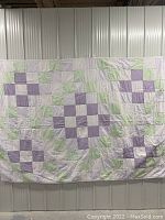 Full view of the quilt showing patchwork grid design with white, light green, and purple checkered squares.