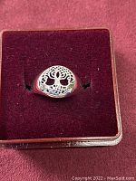 Image of silver-tone ring with Tree of Life design on a burgundy display box.