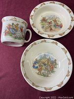 Photo of the full set: heavy bowl with camping scene, smaller bowl with teeter totter scene, and mug featuring rabbits and sleeping grandpa.