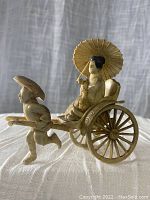 Front side view of the rickshaw driver pulling a two-wheeled cart carrying a seated passenger with umbrella parasol, showcasing detailed molded plastic design with some looseness in pieces.