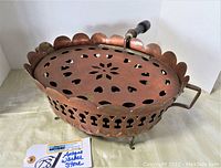 Full view of antique French copper footed warmer stove showing scalloped edges, cut-out heart shapes on lid, and wooden handle.