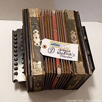 Full view of the antique Weidlich accordion showing bellows, buttons, and tags.