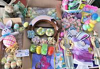 Overview of lot showing wide variety of Easter decorations including plastic eggs, plush bunnies, fabric dolls, basket grass wreath with fabric flowers, and gift bags.