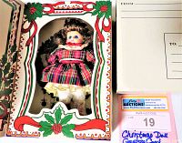 Front view of Marie Osmond porcelain Christmas doll in original box featuring decorative Christmas holly design.