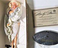 Marilyn Monroe doll in silver gown and shoes, certificate of authenticity and display stand in the box