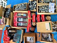 Photo of assorted new old stock hardware including window locks, hasps, door stops and other components in original boxes and packaging on a blue cloth surface.