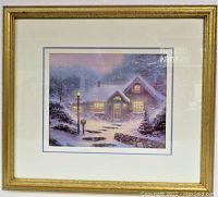 Frontal view of framed art showing cottage scene in snow with warm lights