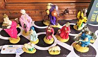 Photo showing all 11 nativity figurines displayed on a patterned cloth, including the Three Wise Men in robes, shepherds, and sheep without baby Jesus.