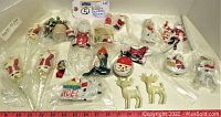 Photo showing a variety of small vintage Christmas decorations spread on a flat surface, including Santa figurines, deer, Noel sign, and other small Christmas items mostly in plastic bags.