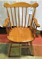 Front view of vintage Windsor wooden chair showing curved top rail, spindle backrest, armrests and sculpted seat.