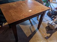 Full view of the wooden library table or desk, showing the rectangular top with heavy surface wear and four straight legs.