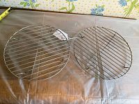Top view of two round metal cooling racks side by side on a countertop with floral wallpaper background.
