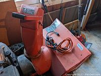 Side view of Ariens ST824 snowblower showing intake chute, electric starter cord, and safety decals.