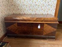 Front view of the Lane Art Deco cedar chest showing the wood veneer finish, waterfall edges and geometric inlay design.