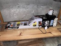 Black & Decker hedge trimmer in original box with battery and charger on wood surface