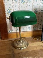 Side view of brass bankers lamp with green cased glass shade showing brass base and shade shape