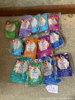 Complete set of 12 plus a duplicate 11 McDonald's 1999 miniature Beanie Babies in original plastic packaging arranged on carpet.