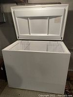 Front view of open white chest freezer showing exterior box and open lid