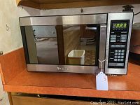 Front view of Magic Chef stainless steel microwave oven showing digital control panel and brand logo.