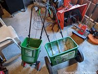 Pair: Scotts broadcast and drop spreader in garage setting.