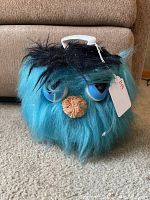 Front view of the blue furry creature shaped record case showing eyes, nose, white handle, and black tuft of hair on top.