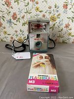 Camera with included box of Sylvania M3 flashbulbs positioned in front, showing the entire lot contents.