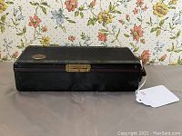 Closed view of the black Bakelite portable radio with clasp, showing its compact rectangular shape and textured surface.