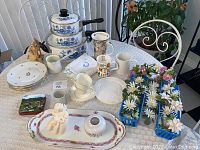 Overview of enamel cookware, porcelain dinnerware, cups, napkins and decorative items on table