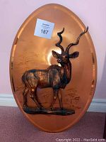 Full view of the oval copper wall art with the metal deer sculpture in relief.