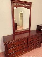 Full front view of solid wood dresser with matching framed mirror.