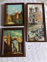 Three framed paintings displayed together showing city scenes and distinctive architecture with figures. Left two paintings have yellow and brown tones; right painting shows a cathedral and outdoor art vendor.