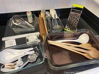 Top view showing large glass baking dishes, wooden spoons, a white ladle, and a metal grater.