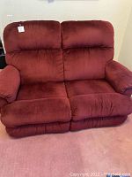 Front view of the burgundy reclining loveseat showing plush cushions and padded armrests.